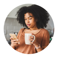 A young woman looking at a cell phone and holding a cup of coffee