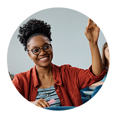 Woman in a classroom smiling and raising her hand